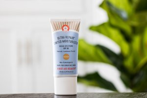 first aid beauty ultra repair tinted moisturizer in front of green plant